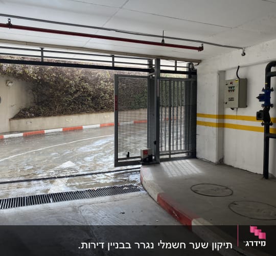 שער חשמלי פתוח בחניון תת קרקעי עם שלט בקרה